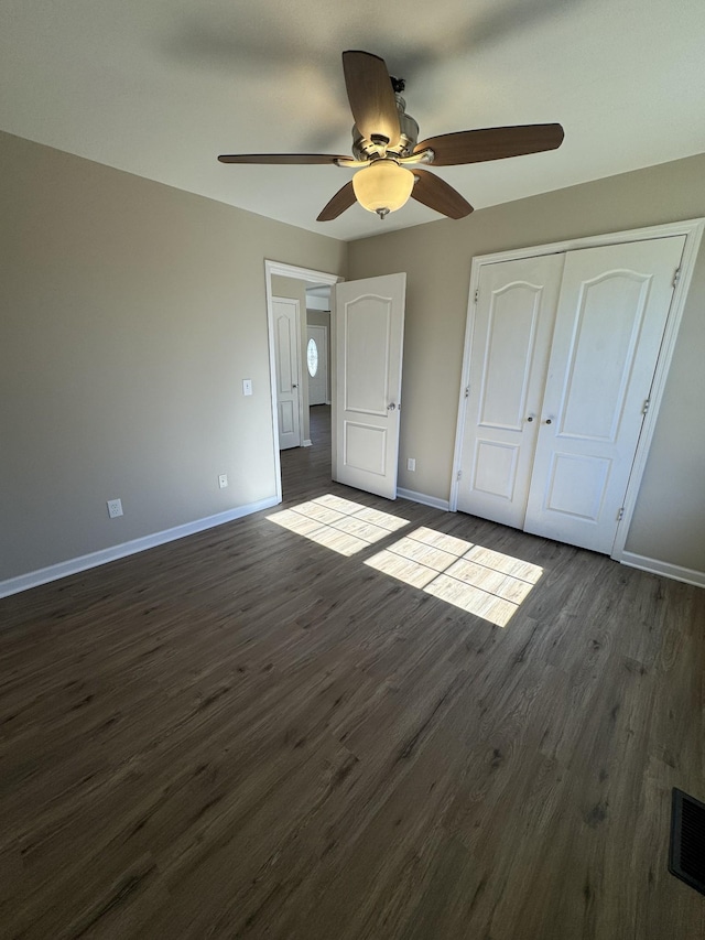 unfurnished bedroom featuring dark wood-type flooring, ceiling fan, and a closet