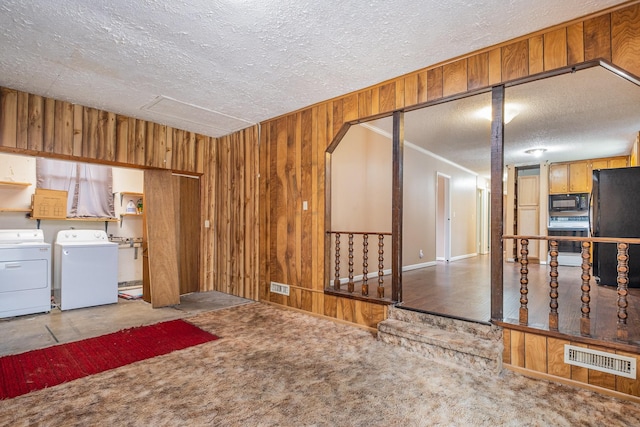 interior space featuring washing machine and dryer, a textured ceiling, and wood walls