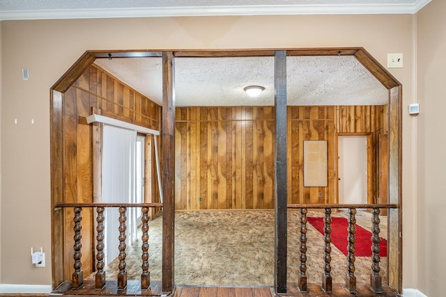 interior space with crown molding, a textured ceiling, and wood walls