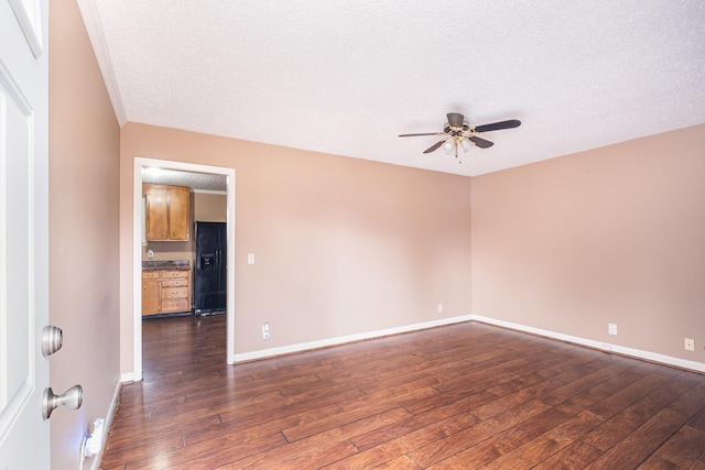 empty room featuring ceiling fan, dark wood-type flooring, and a textured ceiling