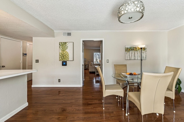 dining space featuring crown molding, dark hardwood / wood-style floors, and a textured ceiling