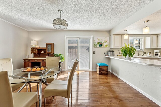 dining space featuring wood-type flooring, sink, and a textured ceiling