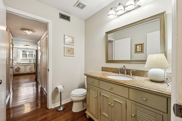 bathroom featuring wood-type flooring, vanity, and toilet