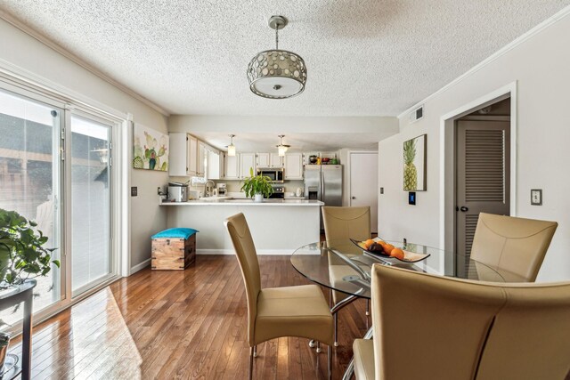 dining area featuring ornamental molding, a textured ceiling, and light hardwood / wood-style flooring