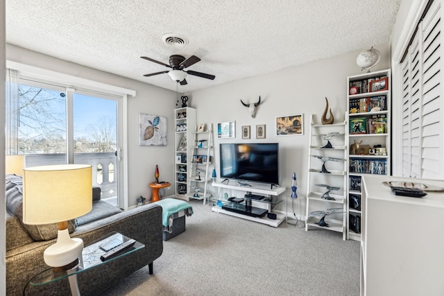 carpeted living room with ceiling fan and a textured ceiling