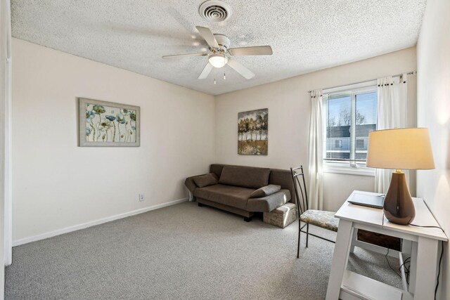 sitting room with ceiling fan, carpet flooring, and a textured ceiling