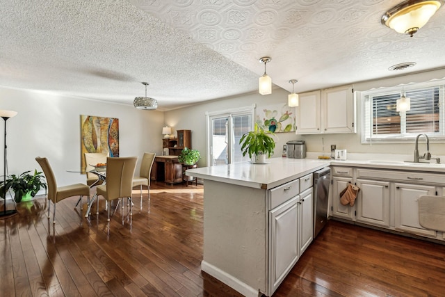 kitchen featuring sink, hanging light fixtures, dark hardwood / wood-style floors, stainless steel dishwasher, and kitchen peninsula