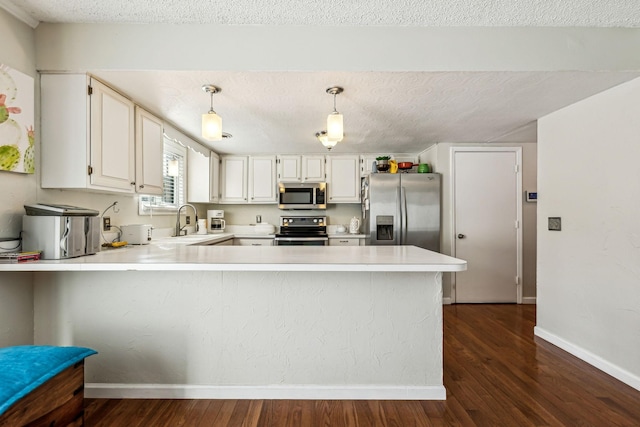 kitchen featuring white cabinetry, stainless steel appliances, kitchen peninsula, and hanging light fixtures