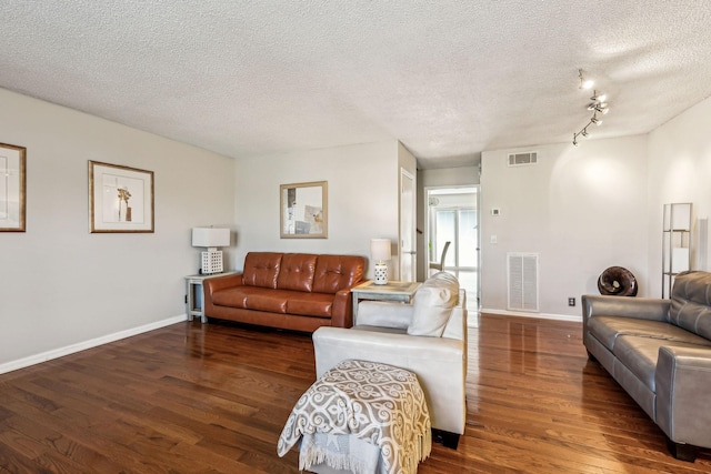 living room featuring track lighting, dark hardwood / wood-style flooring, and a textured ceiling