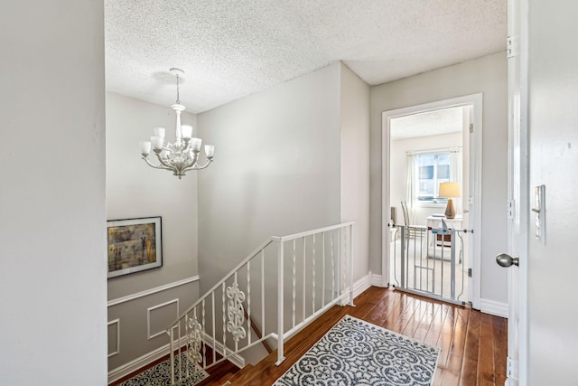 entrance foyer with a textured ceiling, a notable chandelier, and dark hardwood / wood-style flooring