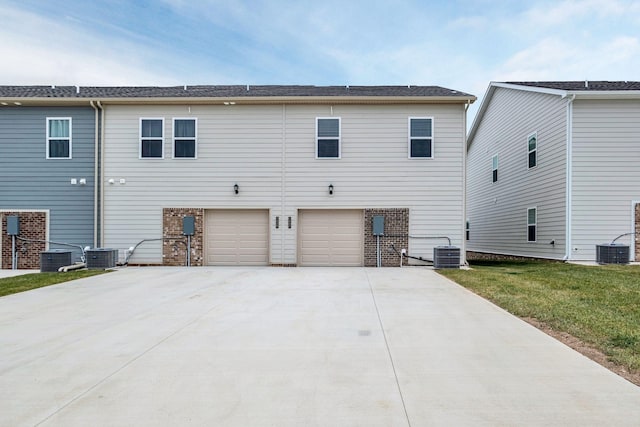 back of property with a garage and central AC