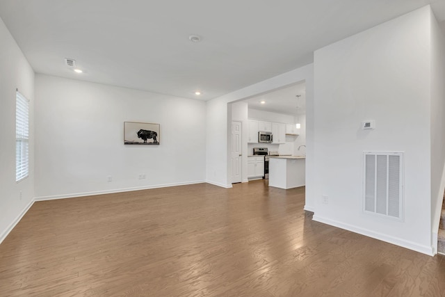 unfurnished living room featuring dark hardwood / wood-style floors and sink