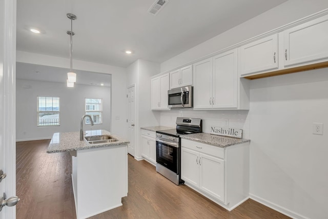 kitchen featuring sink, white cabinetry, hanging light fixtures, stainless steel appliances, and an island with sink