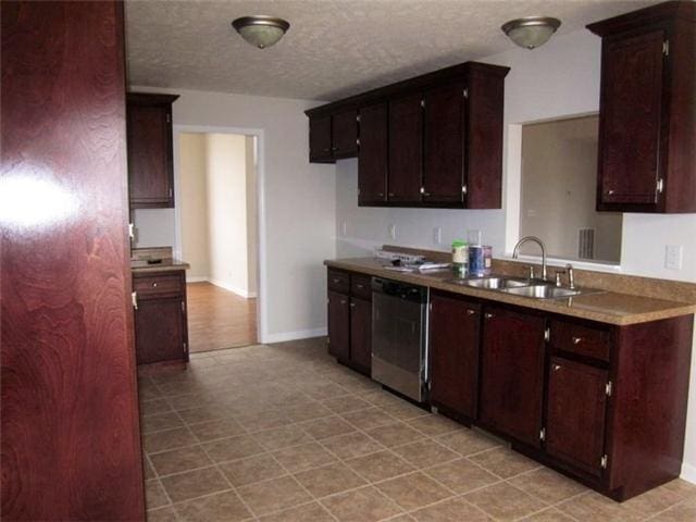 kitchen featuring sink, dark brown cabinets, stainless steel dishwasher, and a textured ceiling