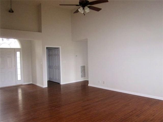 foyer featuring a towering ceiling, dark hardwood / wood-style floors, and ceiling fan