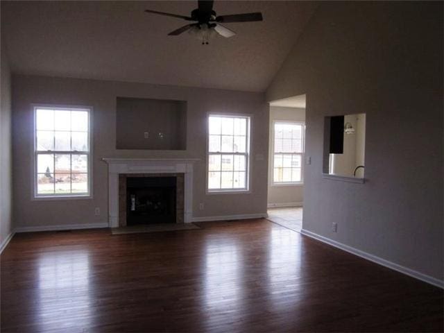 unfurnished living room featuring lofted ceiling, a high end fireplace, dark hardwood / wood-style floors, and ceiling fan