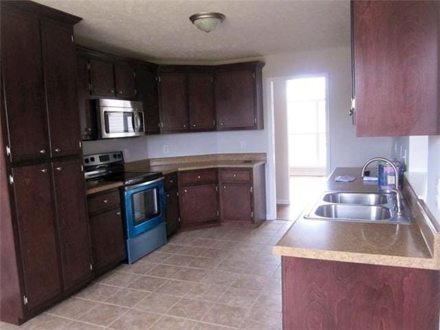 kitchen featuring appliances with stainless steel finishes, sink, and dark brown cabinetry