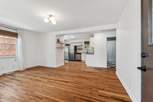 unfurnished living room featuring plenty of natural light and light hardwood / wood-style floors