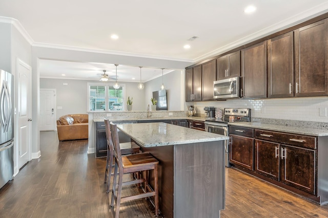 kitchen with sink, stainless steel appliances, dark brown cabinetry, decorative light fixtures, and kitchen peninsula