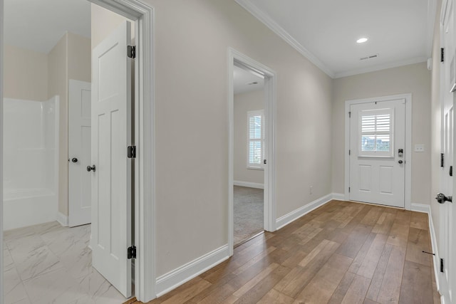 entryway with light hardwood / wood-style flooring, ornamental molding, and a healthy amount of sunlight