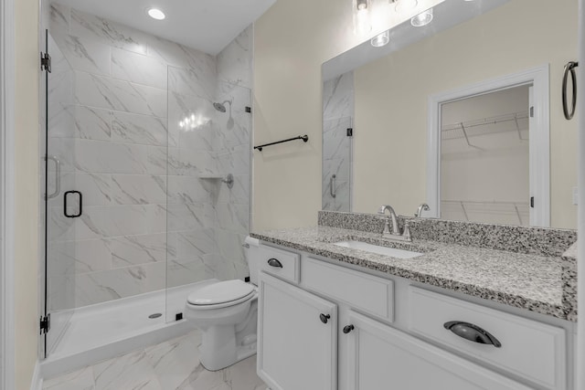 bathroom featuring vanity, a shower with shower door, and toilet