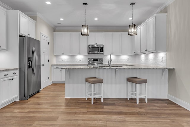 kitchen featuring stainless steel appliances, white cabinetry, and light stone counters