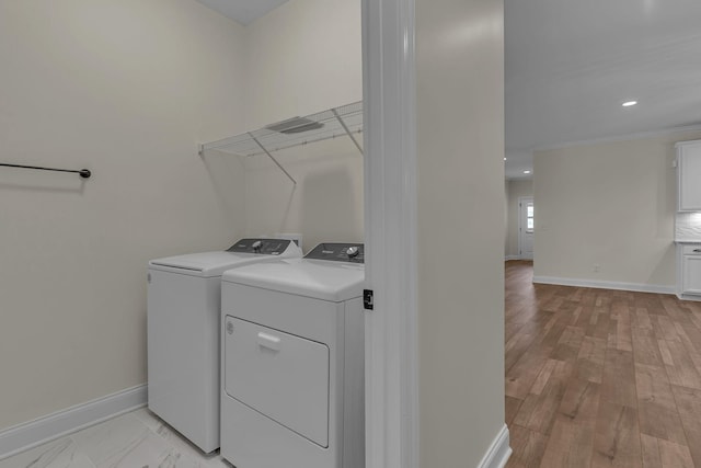 laundry room featuring crown molding, light wood-type flooring, and washer and clothes dryer