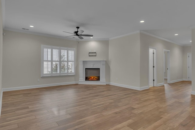 unfurnished living room featuring ornamental molding, a premium fireplace, ceiling fan, and light wood-type flooring