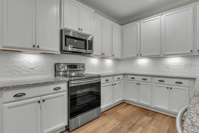 kitchen with light stone counters, light hardwood / wood-style flooring, appliances with stainless steel finishes, decorative backsplash, and white cabinets