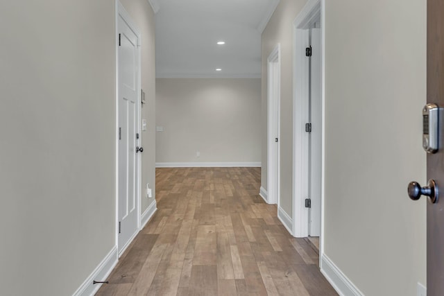 hallway with crown molding and light hardwood / wood-style flooring