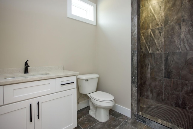 bathroom featuring a tile shower, toilet, vanity, and baseboards