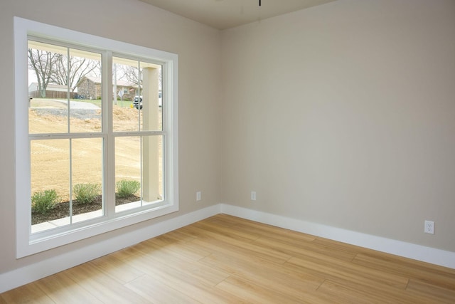unfurnished room featuring baseboards, plenty of natural light, and light wood finished floors