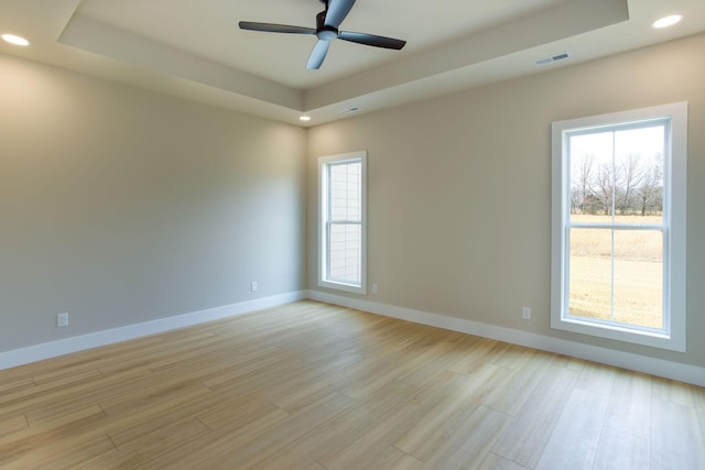 spare room with a raised ceiling, a healthy amount of sunlight, and visible vents