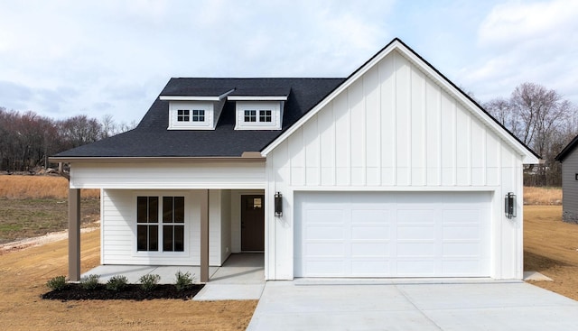 modern farmhouse featuring an attached garage, covered porch, a shingled roof, concrete driveway, and board and batten siding