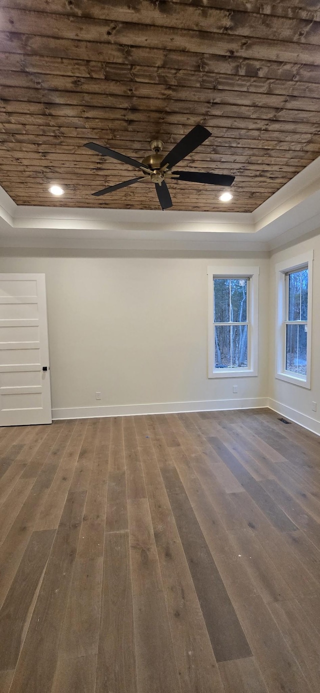 empty room with a tray ceiling, dark hardwood / wood-style flooring, and wooden ceiling