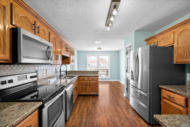 kitchen featuring brown cabinets, dark wood finished floors, stainless steel appliances, backsplash, and a sink