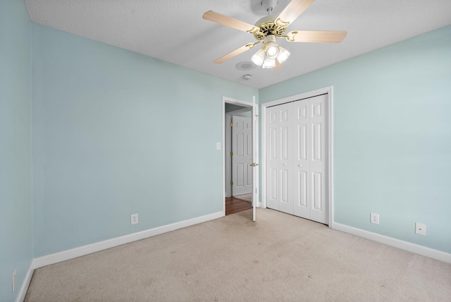 unfurnished bedroom featuring baseboards, a ceiling fan, carpet flooring, a textured ceiling, and a closet