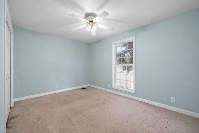 empty room with carpet floors, ceiling fan, baseboards, and a textured ceiling