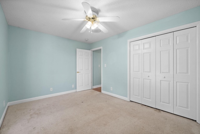 unfurnished bedroom featuring a closet, a ceiling fan, carpet flooring, a textured ceiling, and baseboards