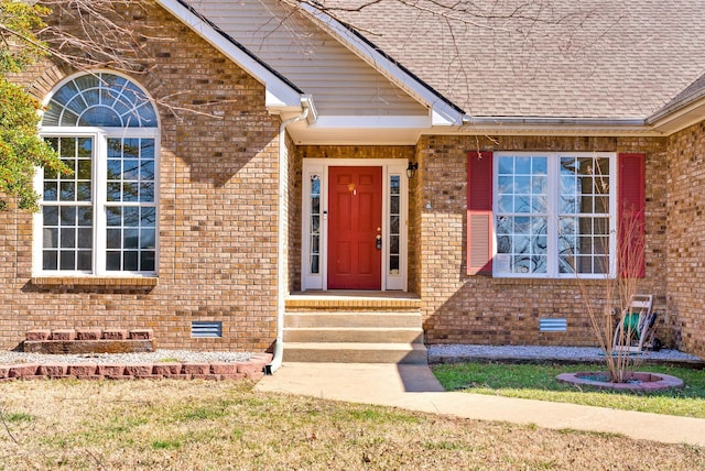 doorway to property with roof with shingles, brick siding, and crawl space