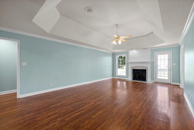 unfurnished living room featuring a fireplace with flush hearth, a tray ceiling, a textured ceiling, and wood finished floors