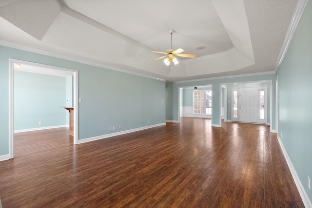 unfurnished living room featuring a tray ceiling, crown molding, baseboards, and wood finished floors