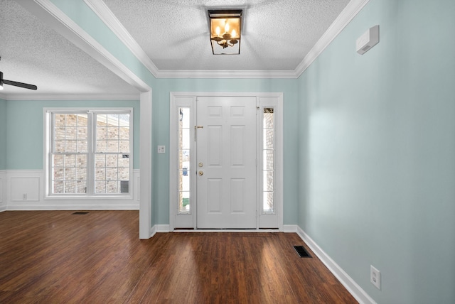 entrance foyer featuring crown molding, a textured ceiling, visible vents, and wood finished floors