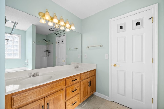 bathroom with double vanity, walk in shower, a sink, and tile patterned floors