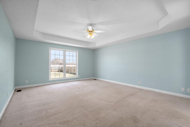 spare room with ceiling fan, a raised ceiling, and baseboards