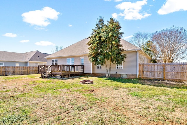 back of house with a yard, an outdoor fire pit, a fenced backyard, and a wooden deck