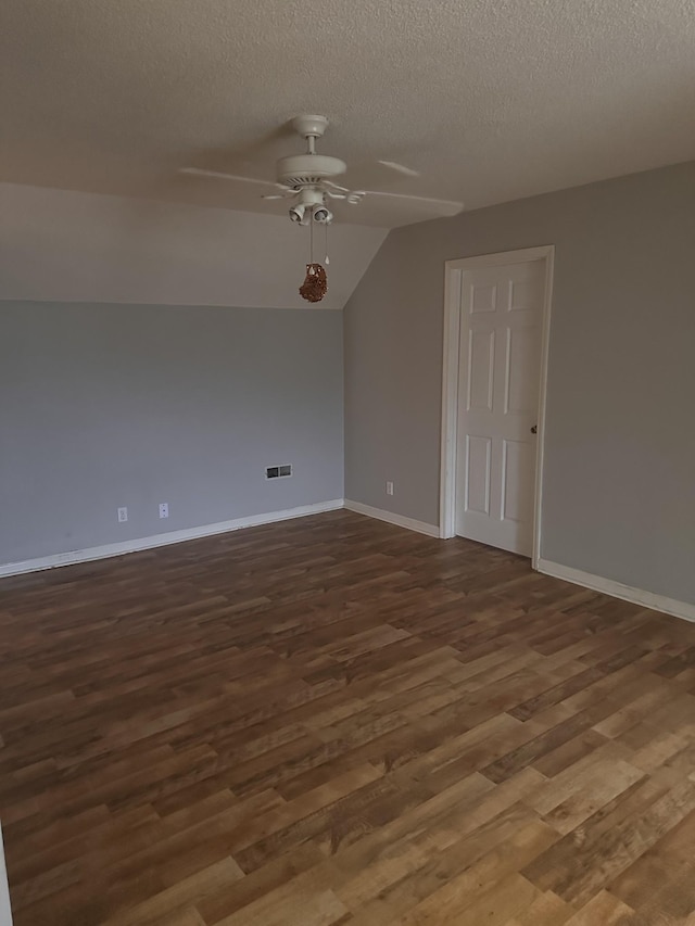 spare room with ceiling fan, dark wood-type flooring, a textured ceiling, and vaulted ceiling