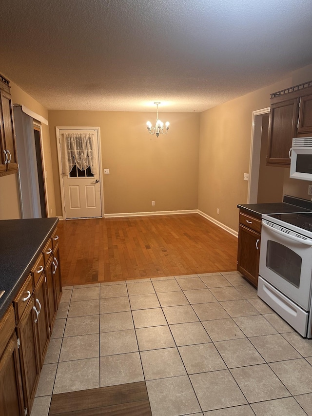 kitchen featuring pendant lighting, light tile patterned floors, white appliances, an inviting chandelier, and a textured ceiling