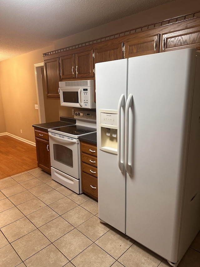 kitchen with light tile patterned floors, white appliances, and a textured ceiling