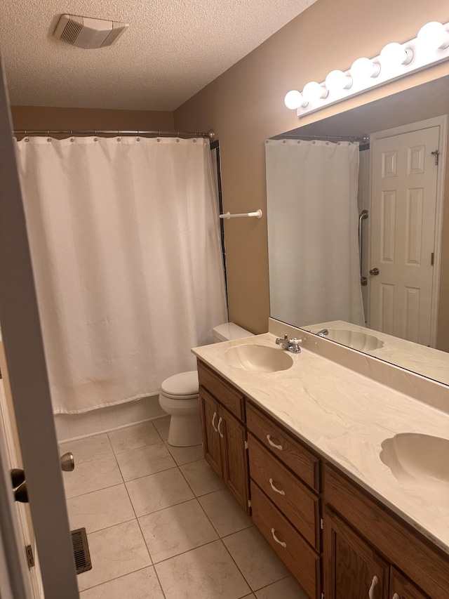 bathroom featuring vanity, tile patterned floors, a textured ceiling, and toilet